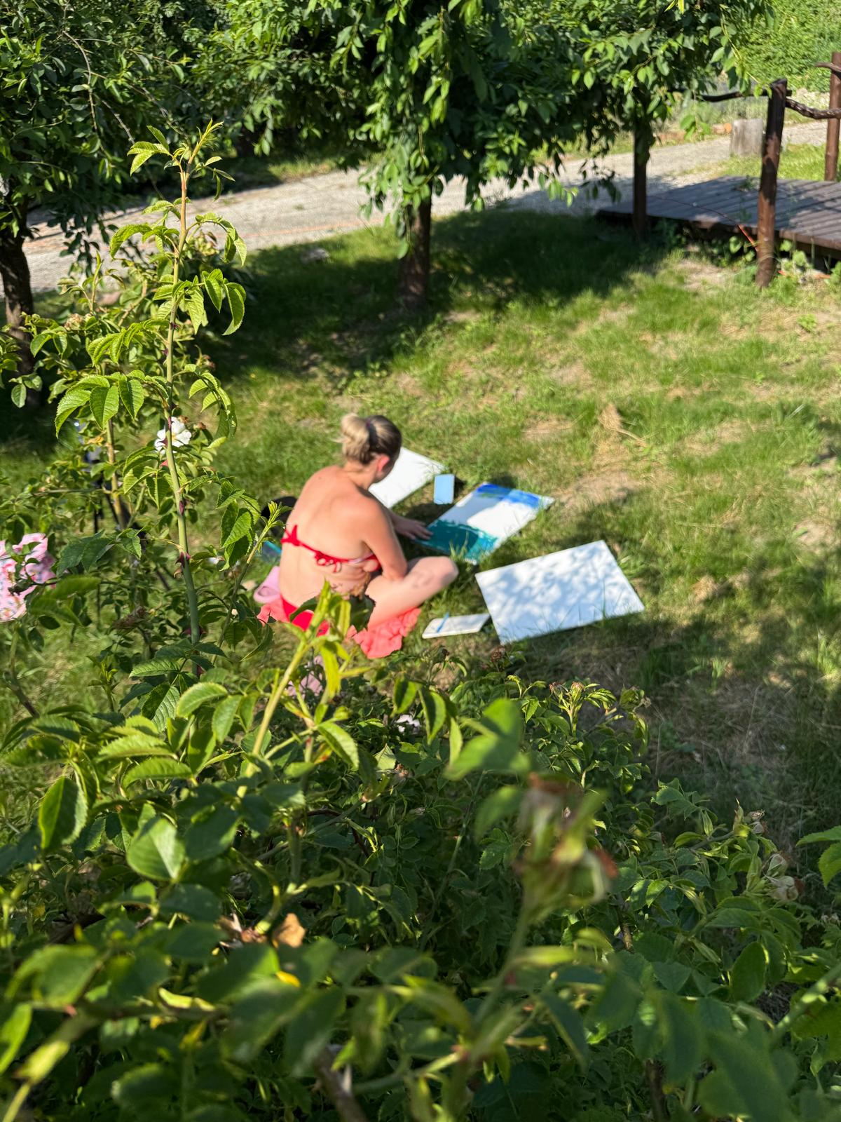 Malowanie na trawie wśród zieleni, płótna rozłożone między krzewami